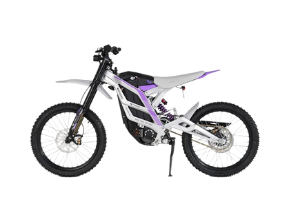 79BIKE Valge-lilla elektriline maastikumootorratas kärniliste rehvide, musta istme ja nähtava vedrustussüsteemiga, kujutatud külgvaates valgel taustal.
